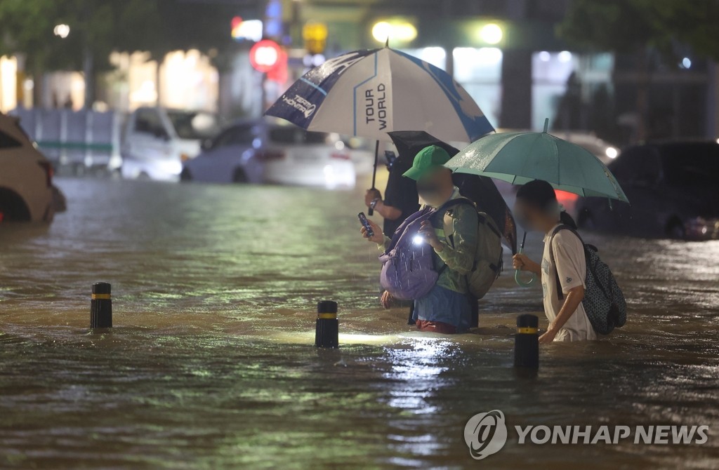 물에 잠긴 도로 헤쳐나가는 시민들