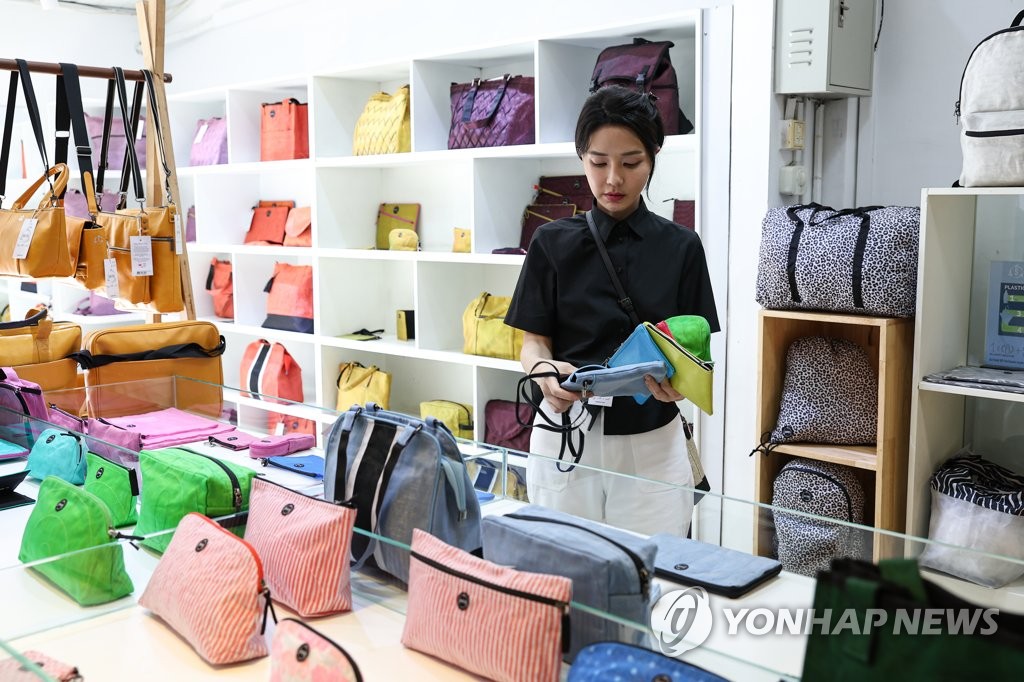 First lady Kim Keon-hee looks at bags made by upcycling firm Smateria during a visit to the company's office in Phnom Penh on Nov. 12, 2022, in this photo provided by the presidential office. (PHOTO NOT FOR SALE) (Yonhap)