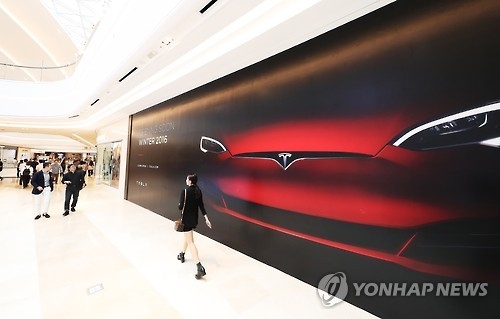 Visitors to Starfield Hanam, a shopping mall east of Seoul, walk past an ad by Tesla on Sept. 5, 2016. The U.S. electric vehicle maker will open its first showroom in Korea at the mall. (Yonhap)