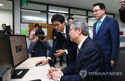 Yim Jong-yong, head of the Financial Services Commission, is briefed on a technology financing system by an official at Shinhan Bank in Seoul in this file photo dated on April 21, 2016. (Yonhap)
