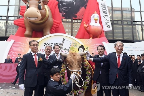 Yim Jong-yong (R), chairman of the Financial Services Commission, poses for a photo with a bull during a ceremony to mark the opening of this year's stock trading at the Seoul bourse on Jan. 2, 2017. (Yonhap)