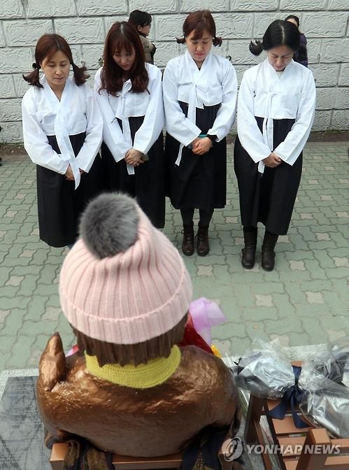 Women wearing "chima jeogori," traditional Korean female attire, offer a silent prayer toward a statue symbolizing women forced to work at wartime Japanese military brothels in front of the Japanese Consulate in the southern South Korean port city of Busan on Jan. 6, 2017. South Korea expressed "strong regret" over Japan's decision to recall its top envoy in Seoul and its consul general in Busan in protest of the erection of the statue by a civic group late last month. (Yonhap) 
