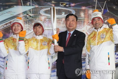 Lee Hee-beom (second from R), head of the organizing committee for the 2018 PyeongChang Winter Olympics holds up the Olympic torch unveiled on Feb. 9, 2017, at Gangneung Hockey Centre in Gangneung, Gangwon Province. (Yonhap)