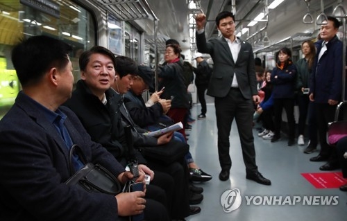 Ahn Cheol-soo (2nd from L), the presidential nominee of the centrist People's Party, talks to a passenger on the subway in Seoul on April 5, 2017. (Yonhap)