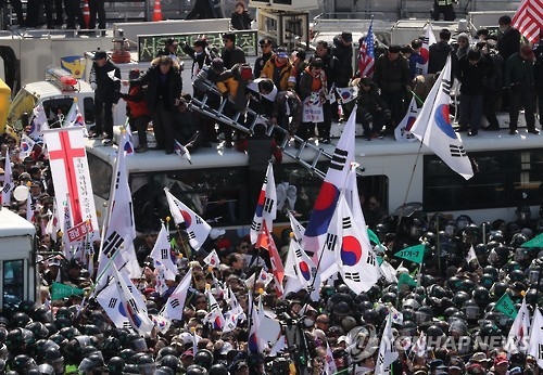 In this photo, taken on March 10, 2017, supporters of ousted President Park Geun-hye attempt to cross over the barricades of police buses during a protest held against the Constitutional Court's decision to remove her from office on the same day. (Yonhap) 