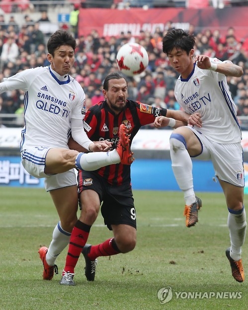 In this file photo taken on March 5, 2017, Suwon Samsung Bluewings defenders Lee Jung-soo (L) and Koo Ja-ryong (R) vies for the ball against FC Seoul forward Dejan Damjanovic during their K League Classic match at Seoul World Cup Stadium in Seoul. (Yonhap)