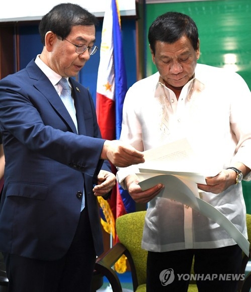 Philippine President Rodrigo Duterte (R) reads a personal letter from South Korean President Moon Jae-in that was presented by Seoul Mayor Park Won-soon, Moon's special envoy to the Association of Southeast Asian Nations (ASEAN), in the southern Philippine city of Davao on May 22, 2017, in this provided photo. (Yonhap)