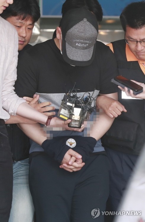 The suspect in a recent bomb blast at Yonsei University is surrounded by reporters as the police take him to a court on June 15, 2017. (Yonhap) 