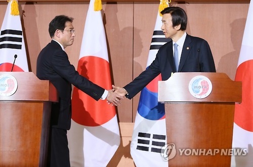 This file photo dated on Dec. 28, 2015, shows then South Korean Foreign Minister Yun Byung-se (R) and Japanese Foreign Minister Fumio Kishida shake hands after announcing an agreement to resolve the issue of Japan's wartime sexual slaver. (Yonhap)
