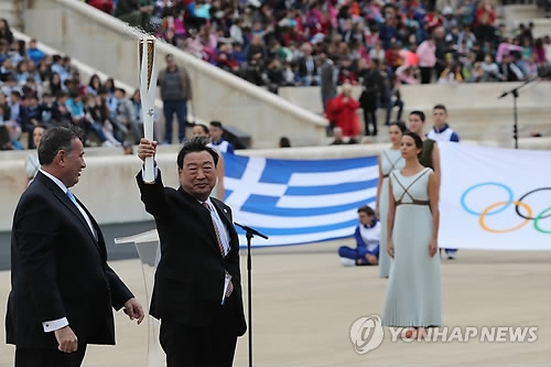 In this file photo taken on Oct. 31, 2017, Lee Hee-beom (2nd from L), the president of the PyeongChang 2018 Organizing Committee, holds the Olympic torch at the Panathenaic Stadium in Athens. (Yonhap)