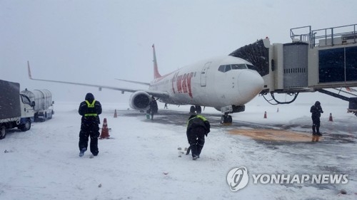 Officials shovel the snow by a gate at Jeju International Airport on Jan. 11, 2018. (Yonhap)