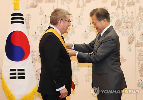 South Korean President Moon Jae-in (R) confers the Cheongryong Medal, the country's highest decoration in the Order of Sport Merit, on International Olympic Committee President Thomas Bach in a ceremony at the presidential office Cheong Wa Dae in Seoul on March 8, 2018. (Yonhap)