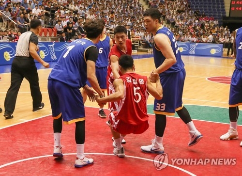 In this Joint Press Corps photo, South Korean players Park Chan-hee (L) and Lee Seung-hyun (R) help Kim Chol-myong of North Korea up during their friendly basketball game at Ryugyong Chung Ju-yung Gymnasium in Pyongyang on July 5, 2018. (Yonhap)