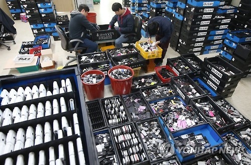 Employees at a used-handset retailer in Uiwang, south of Seoul, inspect devices in this file photo taken June 2, 2016. (Yonhap)