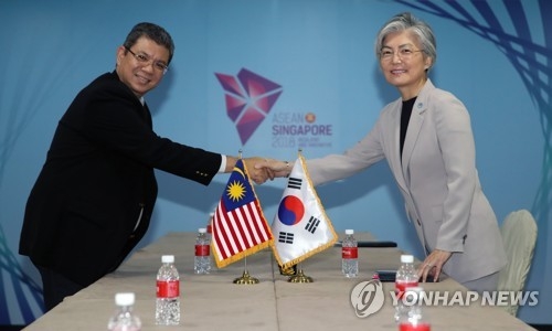 South Korean Foreign Minister Kang Kyung-wha (R) shakes hands with her Malaysian counterpart Saifuddin Abdullah in a Singapore meeting on Aug. 1, 2018. (Yonhap)