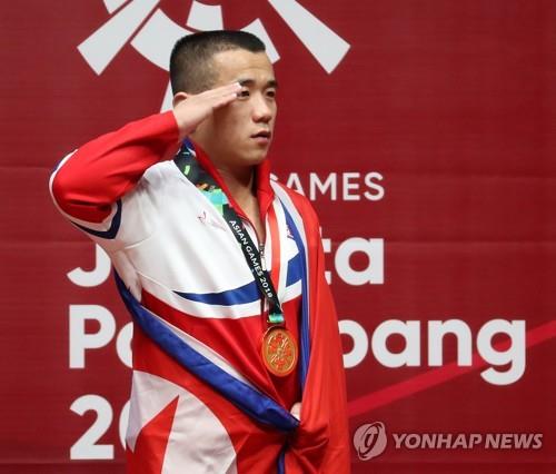 North Korean weightlifter Om Yun-chol salutes the North Korean flag during the medal ceremony of the men's 56kg weightlifting competition at the 18th Asian Games at Jakarta International Expo in Jakarta on Aug. 20, 2018. (Yonhap)