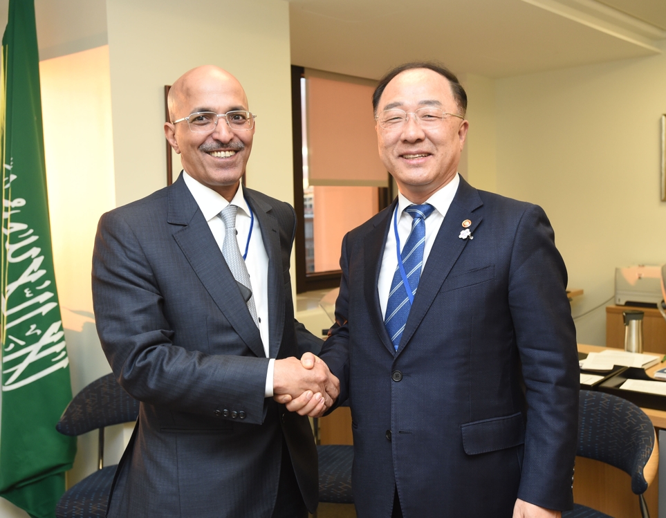 South Korean Finance Minister Hong Nam-ki (R) shakes hands with Saudi Finance Minister Mohammed Al-Jadaan at the IMF headquarters in Washington on Oct. 17, 2019, in this photo provided by the ministry. (PHOTO NOT FOR SALE) (Yonhap)