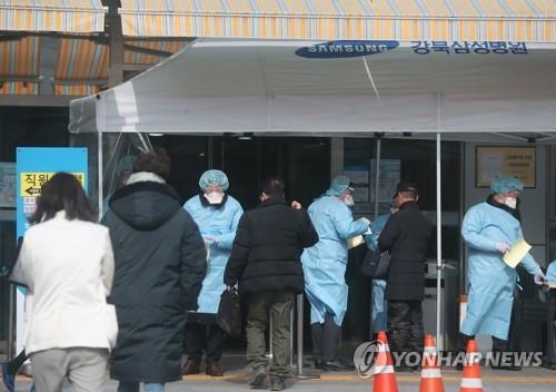 Medical staff check people entering a hospital in Seoul on Feb. 7, 2020 as South Korea further strengthens its effort to combat the novel coronavirus. (Yonhap)