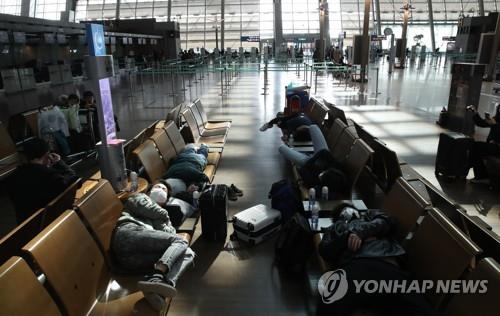 This photo taken Feb. 26, 2020, shows Incheon International Airport, west of Seoul, with foreign tourists in masks resting on seats amid the spreading coronavirus outbreak. (Yonhap) 