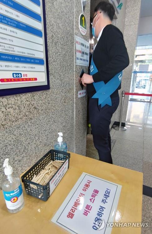 A box containing pieces of disposable wooden chopsticks for pressing elevator buttons is set next to an elevator at the city hall in Gangneung on South Korea's east coast on March 9, 2020, as part of preventive measures against the new coronavirus. (Yonhap)