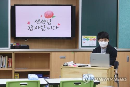Park Min-young, the homeroom teacher of a sixth-grade class, conducts a remote class at an empty classroom in Borame Elementary School in Seoul, on May 15, 2020, Teachers' Day, as South Korea has introduced online classes for elementary, middle and high schools amid the coronavirus pandemic. On the screen is a message in Korean that says, "Mr. Park, Thank You." (Yonhap)