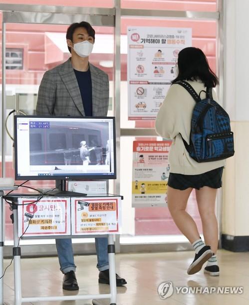 A student passes by a thermal imaging camera set up at a school in Seoul on May 20, 2020. (Yonhap) 