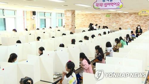 Students eat lunch with opaque partitions separating them at the cafeteria of Daejeon Seonyucho Elementary School in Daejeon, 164 kilometers south of Seoul, on May 27, 2020. (Yonhap) 