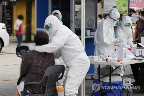 In this photo, taken on Aug. 11, 2020, health workers give a citizen a COVID-19 test at a makeshift clinic near Namdaemun Market in Seoul after eight merchants there tested positive for the virus. (Yonhap)