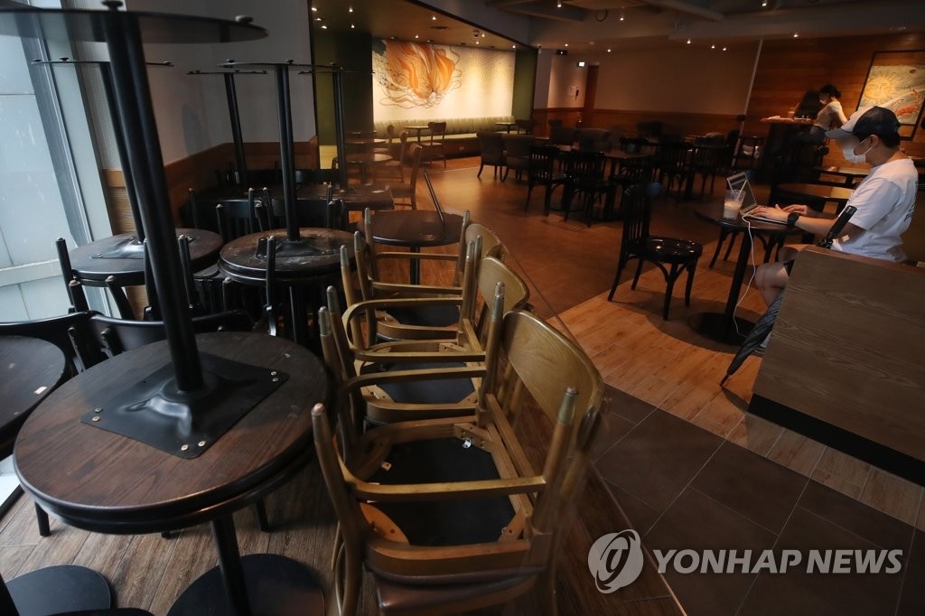 Tables and chairs are moved to a corner of a large cafe in downtown Seoul in preparation for the government's heightened social distancing rules that go into effect on Aug. 30, 2020. Authorities said for the next week, franchise cafes will only be allowed to offer takeout to patrons. South Korea has been trying to stem a spike in coronavirus cases in recent weeks. (Yonhap) 