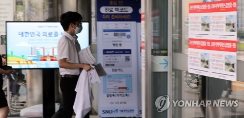 A trainee doctor at Seoul National University Hospital, who earlier held up signs to protest the government's medical reform plan, reenters the hospital after the KMA and parliament reached an agreement. (Yonhap)