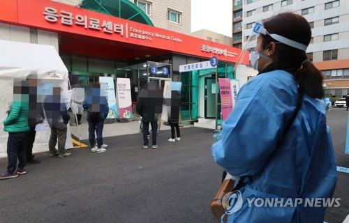 A health worker clad in protective gear guides citizens at a makeshift virus testing clinic in Seoul on Nov. 27, 2020. (Yonhap)