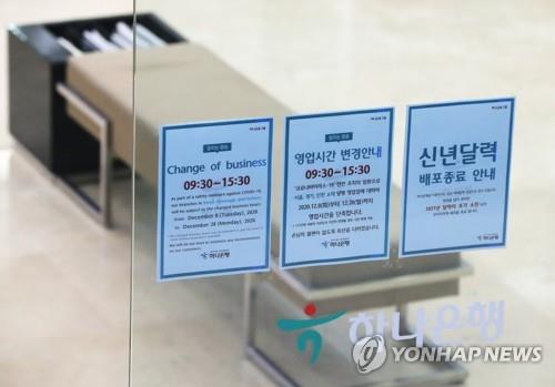 A notice on a glass wall shows that a bank is shortening its operation hours by one hour in this photo taken on Dec. 8, 2020. All banks in the capital area will run from 9:30 a.m. to 3:30 p.m. until Dec. 28 amid rising coronavirus infections. (Yonhap)