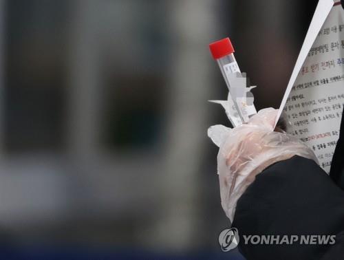 A visitor holds a real-time test kit for the new coronavirus at a public health facility in Seoul on Dec. 17, 2020. 