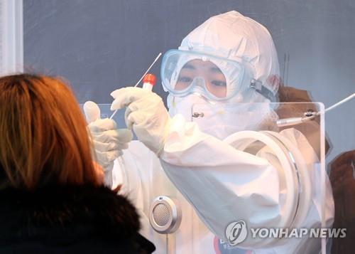 A medical worker conducts a COVID-19 test on a citizen at a temporary testing center set up in front of Seoul Station in central Seoul on Jan. 31, 2021. (Yonhap)