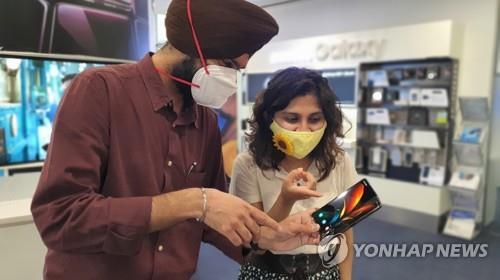 This photo, provided by Samsung Electronics Co. on Sept. 18, 2020, shows consumers looking at the company's Galaxy Z Fold 2 smartphone at a store in Gurugram, India. (PHOTO NOT FOR SALE) (Yonhap)