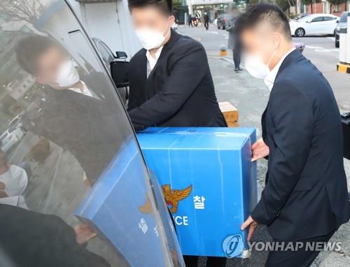 Police officers move a box of items they seized during a search of the city hall of Ansan, 42 km south of Seoul, on March 29, 2021, as part of an investigation into a suspicious land purchase by the wife of a former aide to Interior Minister Jeon Hae-cheol. (Yonhap)