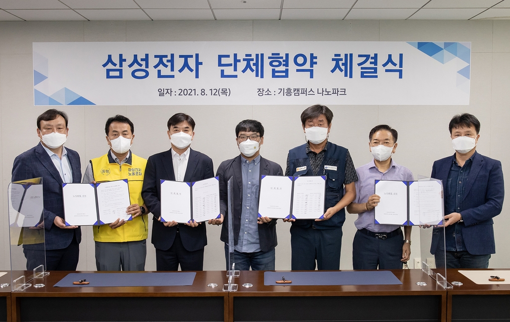 This photo provided by Samsung Electronics Co. on Aug. 12, 2021, shows representatives from the management and the labor union posing for a photo after signing a collective agreement at the company's plant in Yongin, south of Seoul. (PHOTO NOT FOR SALE) (Yonhap)