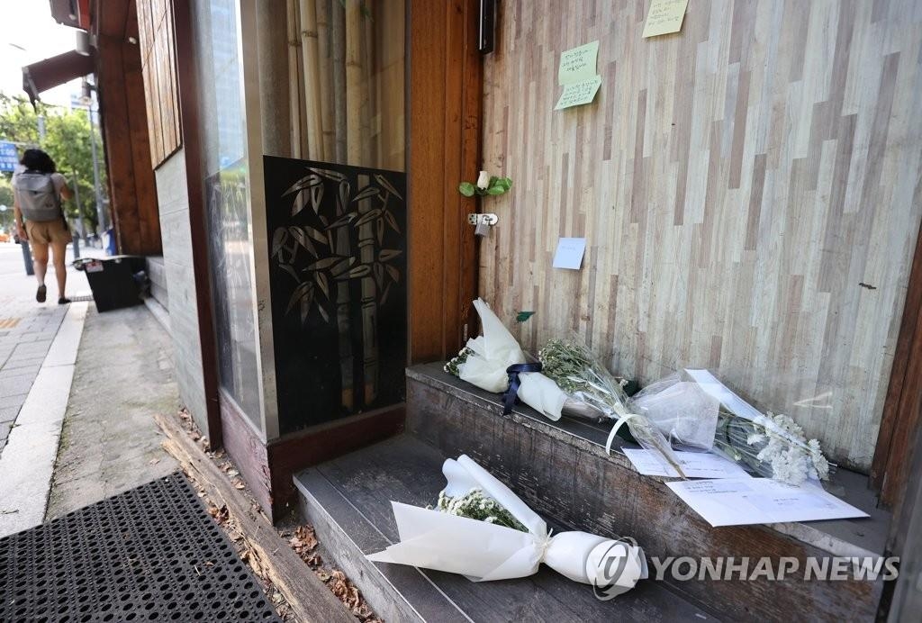 Bouquets of flowers are laid in front of a bar whose owner committed suicide after suffering economic difficulties due to pandemic-related business restrictions in Seoul on Sept. 14, 2021. (Yonhap)