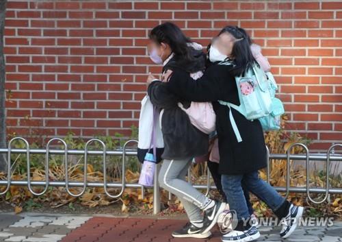 Students greet each other on their way to class at an elementary school in Seoul's Yongsan district on the first day of the full resumption of in-person school attendance on Nov. 22, 2021. (Yonhap)