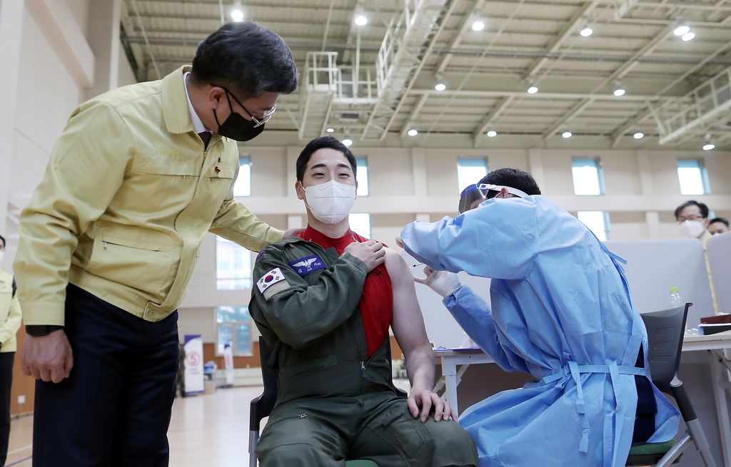 Defense Minister Suh Wook (L) watches an airman get a booster shot at the 15th Special Missions Wing in Seongnam, south of Seoul, on Dec. 16, 2021, in this photo released by the Ministry of Defense. (PHOTO NOT FOR SALE) (Yonhap)