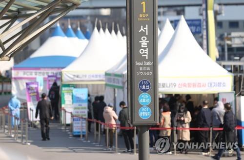 People stand in line to take coronavirus tests at a screening clinic in front of Seoul Station on March 22, 2022. South Korea's new COVID-19 cases spiked to over 350,000 on the day. (Yonhap)