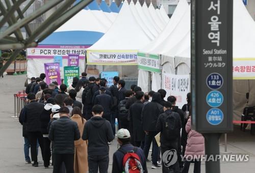 People stand in line to take coronavirus tests at a screening clinic in front of Seoul Station on March 23, 2022.