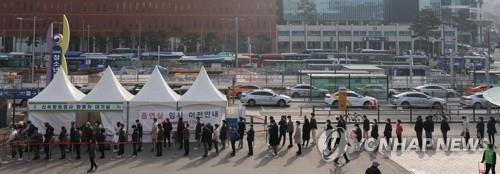 People stand in line to take coronavirus tests at a screening clinic in front of Seoul Station on March 25, 2022. South Korea reported fewer than 400,000 new cases for the second day in a row as the omicron variant tightens its grip on the country. (Yonhap)