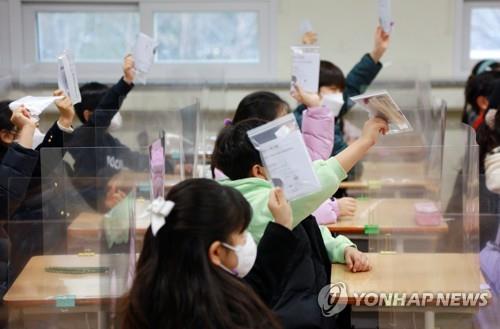 Elementary school students in South Korea's southeastern city of Daegu show COVID-19 self-test kits they received from their teacher on March 2, 2022. (Yonhap)