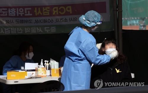A health worker conducts a COVID-19 test at a testing site near Seoul Station in central Seoul on April 7, 2022. (Yonhap)
