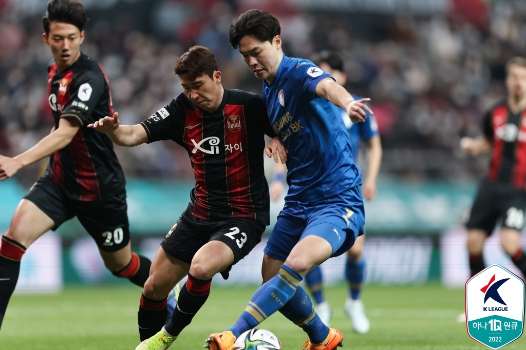 In this April 10, 2022, file photo provided by the Korea Professional Football League, Yoon Jong-gyu of FC Seoul (C) and Kim Gun-hee of Suwon Samsung Bluewings battle for the ball during the clubs' K League 1 match at Seoul World Cup Stadium in Seoul. (PHOTO NOT FOR SALE) (Yonhap)