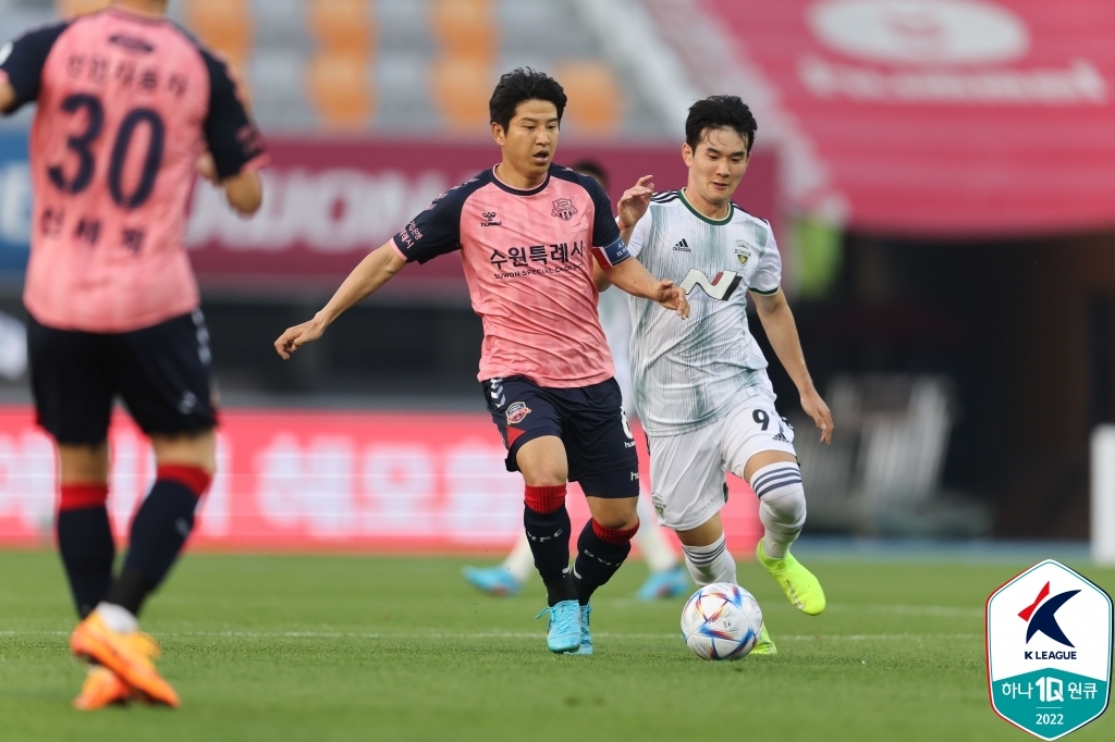 Park Joo-ho of Suwon FC (L) and Kim Jin-gyu of Jeonbuk Hyundai Motors battle for the ball during their clubs' K League 1 match at Suwon Stadium in Suwon, 45 kilometers south of Seoul, on May 22, 2022, in this photo provided by the Korea Professional Football League. (PHOTO NOT FOR SALE) (Yonhap)
