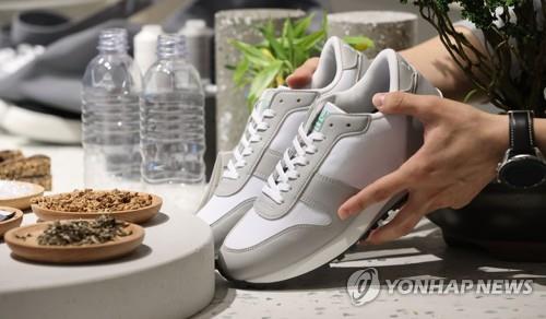 In this file photo taken Oct. 6, 2021, an official shows shoes made with single-use plastics. (Yonhap)