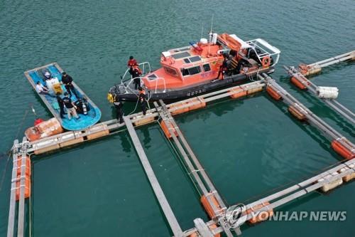 Police approach the location of the missing Cho family's car, spotted hanging on the fences of a fish cage farm, some 80 meters off the Songgok dock on Sinji Island, Wando County, on June 28, 2022. (Yonhap)
