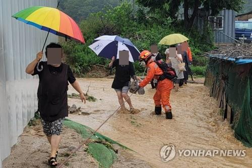 This photo, provided by the Gyeonggi fire office on June 30, 2022, shows residents in Yangju, Gyeonggi Province, evacuating with the help of officers. (PHOTO NOT FOR SALE) (Yonhap)